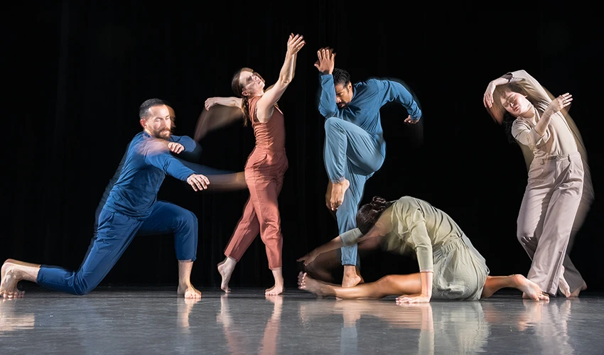 photo of dancers posing in jumpsuits against a dark backdrop